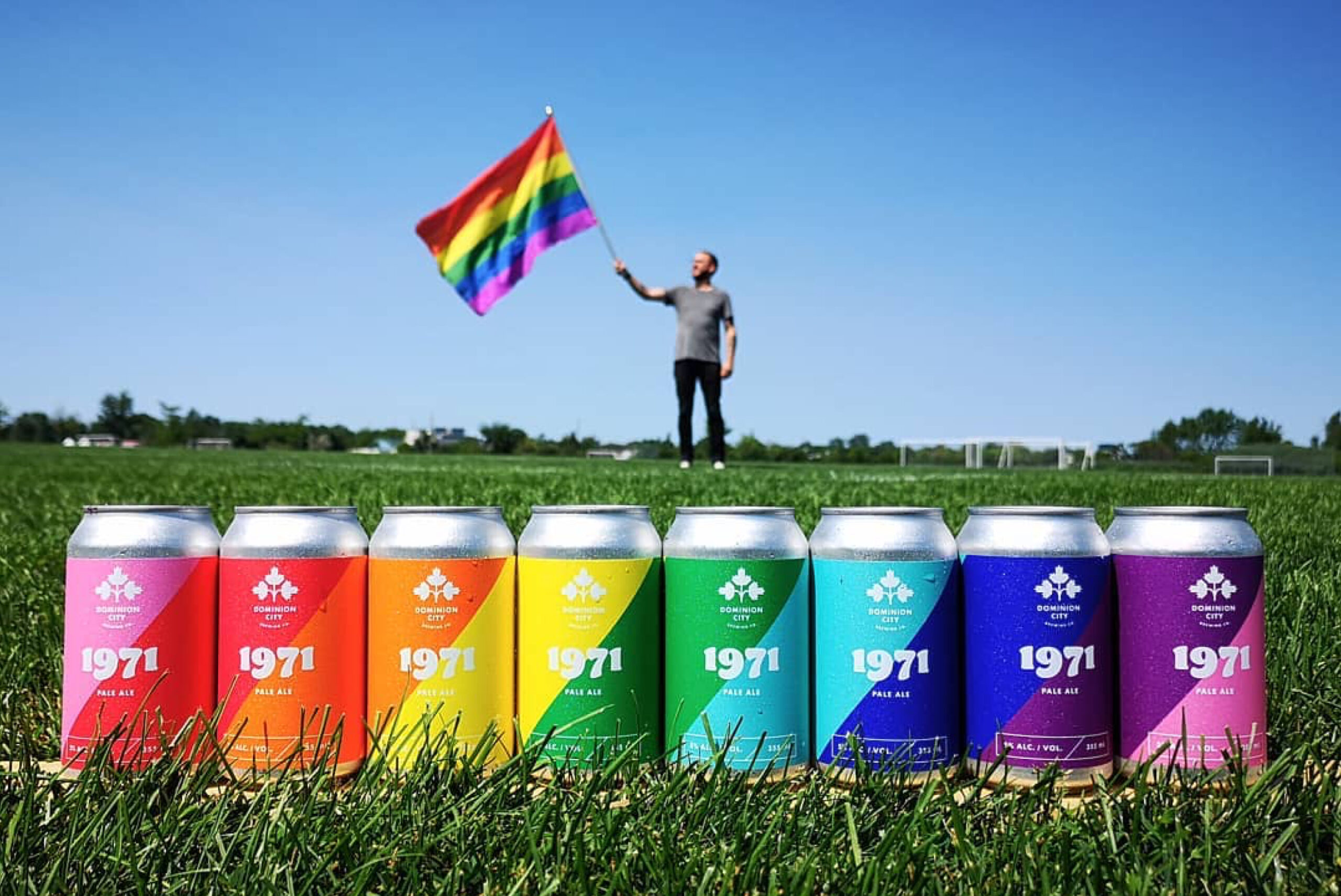 Line up of Dominion City's Pride-inspired beer, 1971 with an employee holding an LGBTQ+ flag.