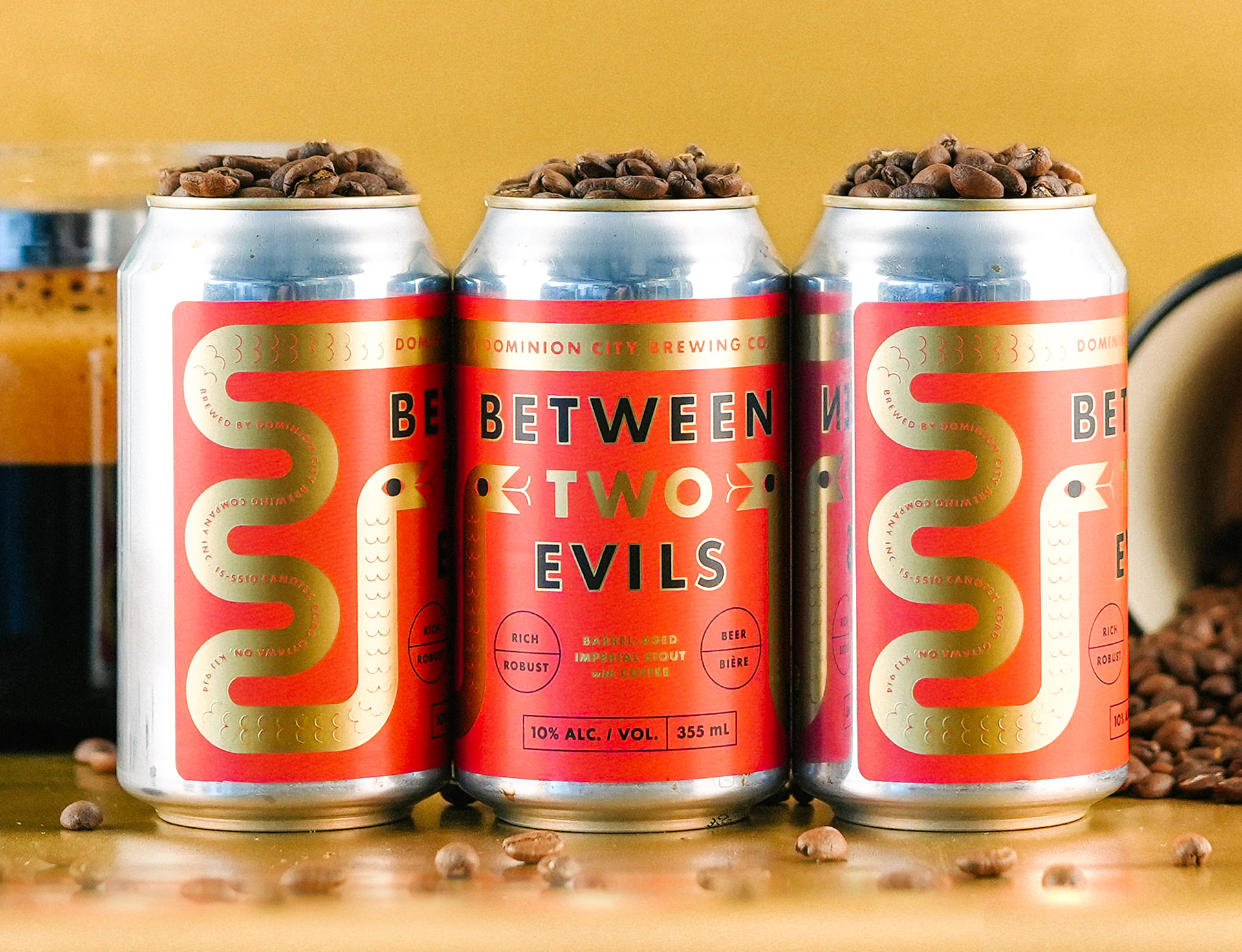 A can for a stout called Between Two Evils, which features a red label with gold foil snakes.