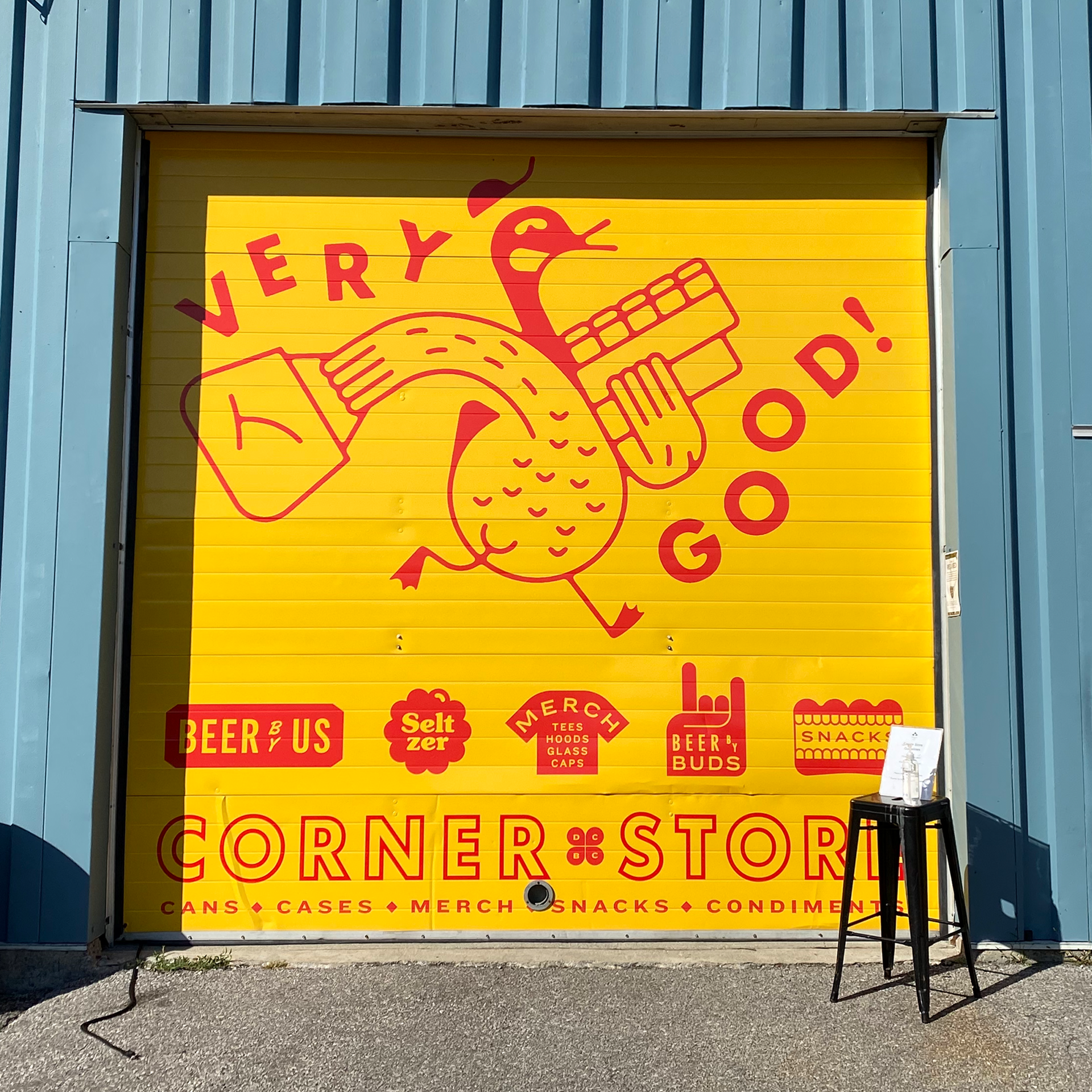 Large yellow garage door design for Dominion City's Corner Store. Featuring a goose with the words "Very Good!".